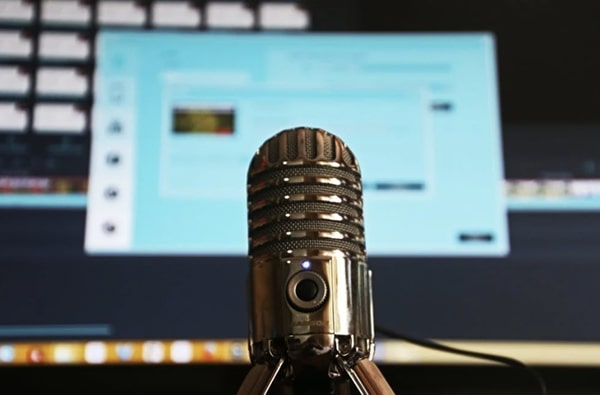 Beauty shot of zoomed in shiny-looking, vintage microphone against blurry desktop view on computer screen