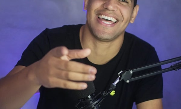 Straight forward view of a young man smiling and pointing close up to the camera with microphone